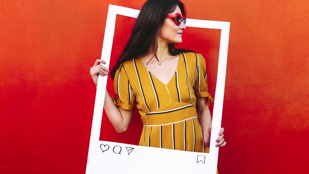 Woman holding a black social media photo frame in hand